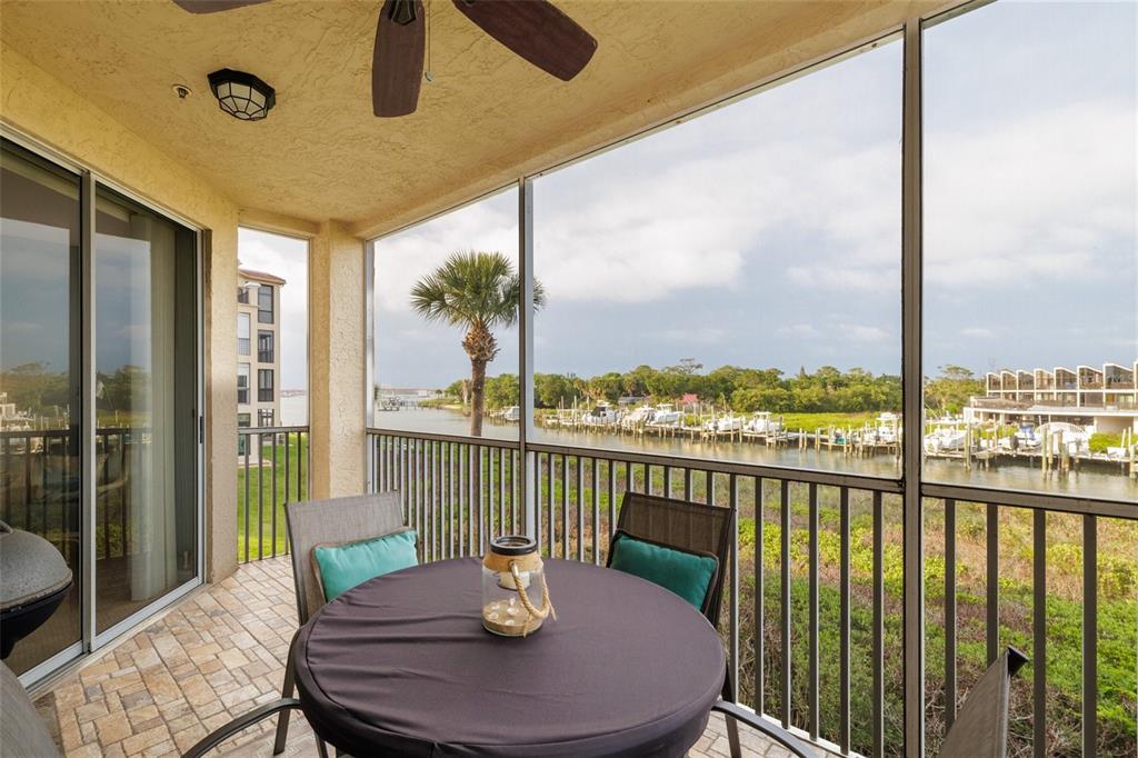 A screened-in balcony with a table and chairs overlooks a marina and waterway — 434 BOUCHELLE DRIVE UNIT 203, NEW SMYRNA BEACH, FL