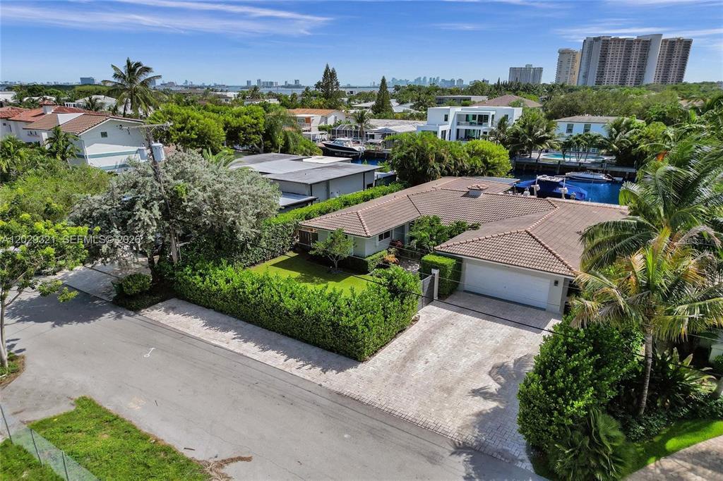 An aerial view shows a single-story house with a tiled roof, driveway, and backyard pool — 1912 NE 119TH ROAD, NORTH MIAMI, FL
