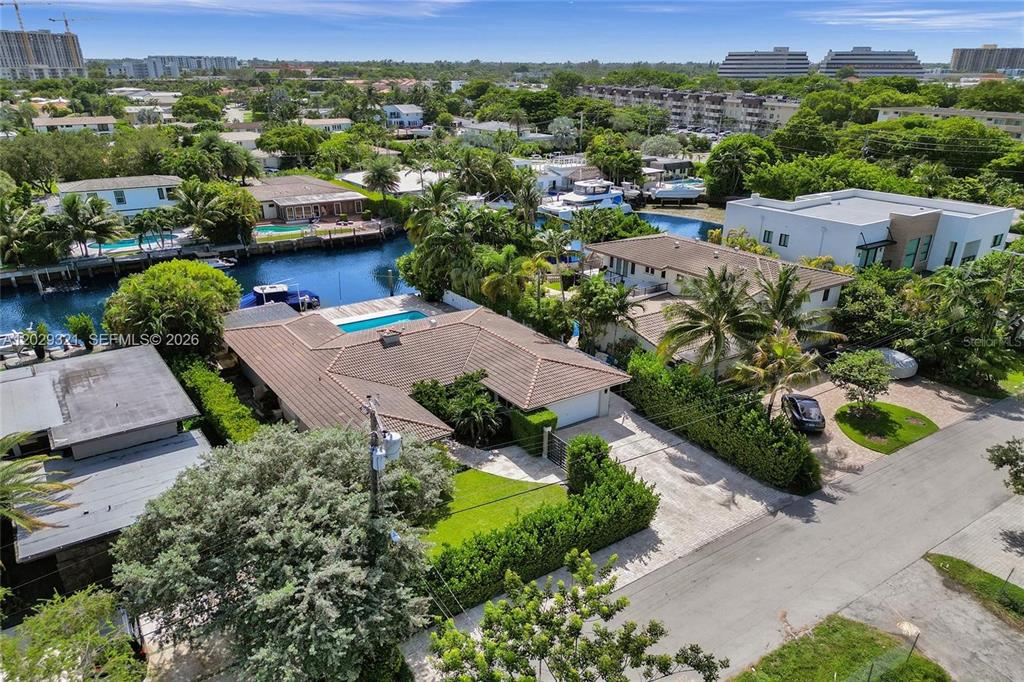 An aerial view shows a waterfront house with a pool, tiled roof, and paved driveway — 1912 NE 119TH ROAD, NORTH MIAMI, FL