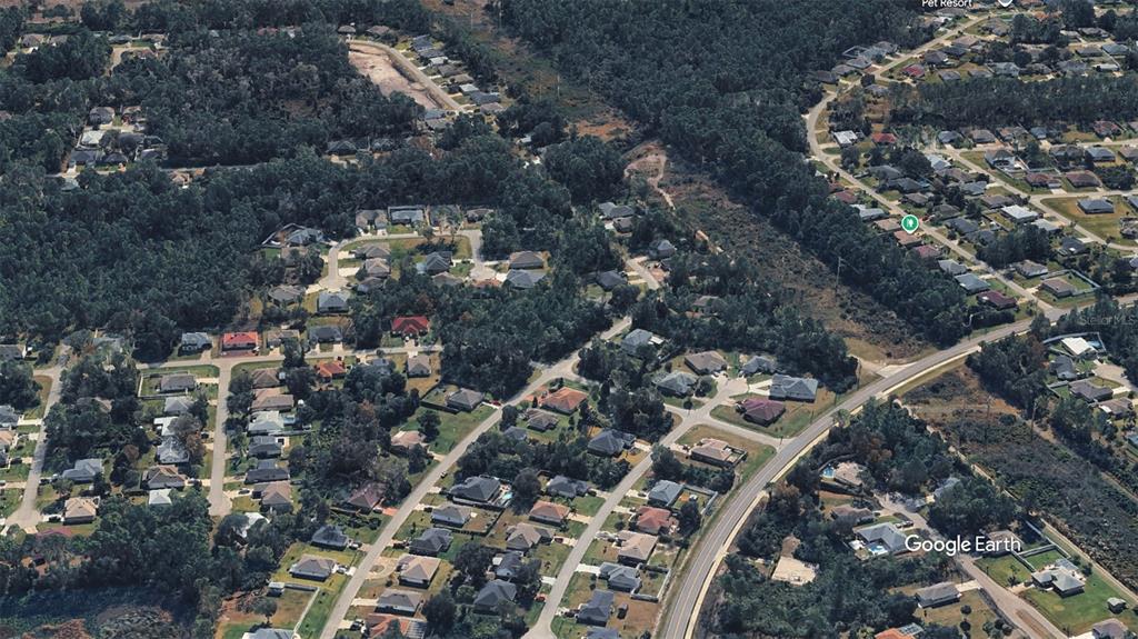 This aerial view shows a suburban neighborhood with houses surrounded by dense wooded areas — 3 SECRETARY TRAIL, PALM COAST, FL