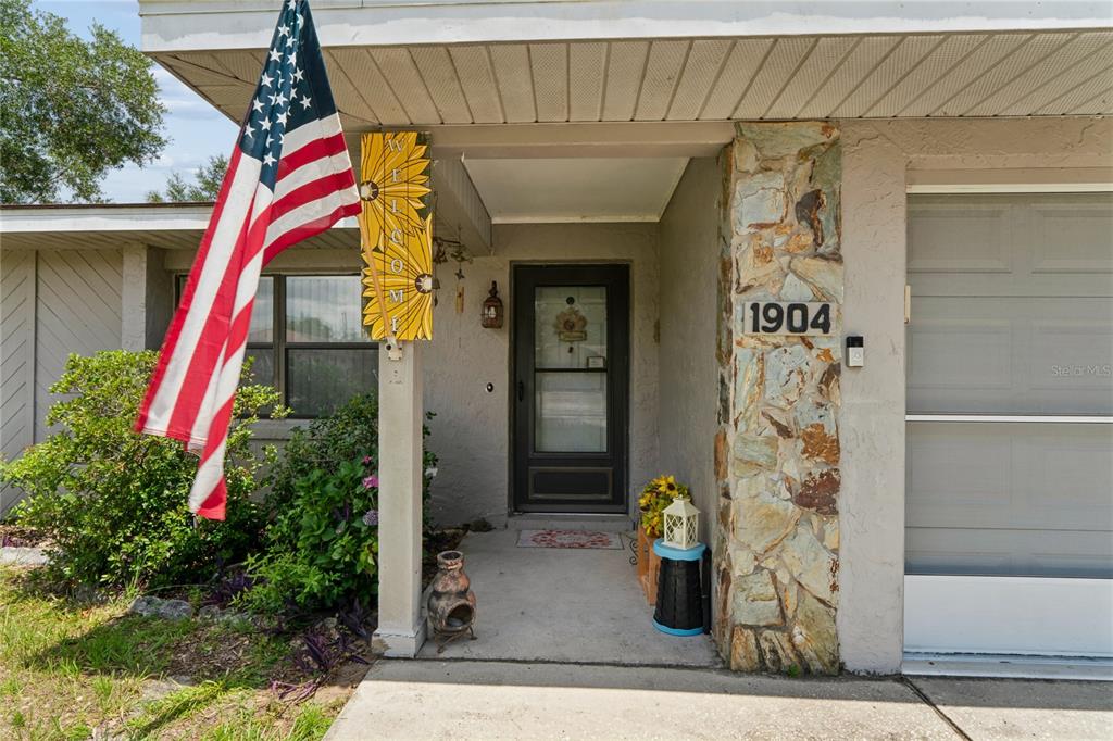 The front exterior of a house features a stone pillar, a front door, and a flag — 1904 W BELGRADE DRIVE, CITRUS SPRINGS, FL