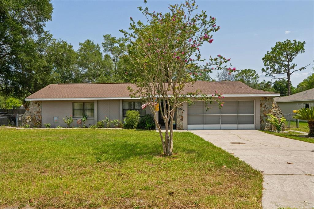 A single-story house with a stone-accented facade, a concrete driveway, and a front lawn — 1904 W BELGRADE DRIVE, CITRUS SPRINGS, FL