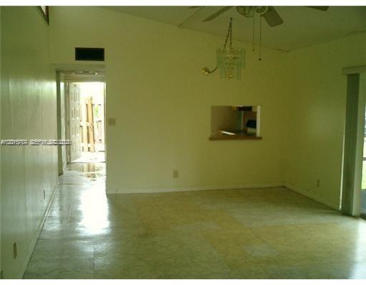 An empty room with light-colored walls, tile flooring, a ceiling fan, and a kitchen pass-through — 5702 Swordfish Cir, Tamarac FL 33319, TAMARAC, FL