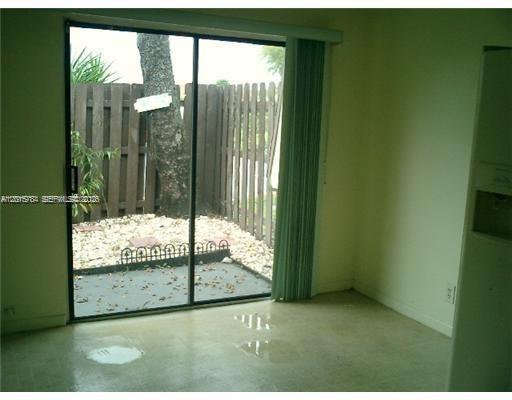 A room with a sliding glass door leading to a small, fenced-in patio area — 5702 Swordfish Cir, Tamarac FL 33319, TAMARAC, FL