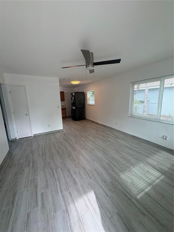 An empty room with gray wood-look tile flooring, a ceiling fan, and a stacked washer-dryer — 364 3RD STREET NW, LARGO, FL