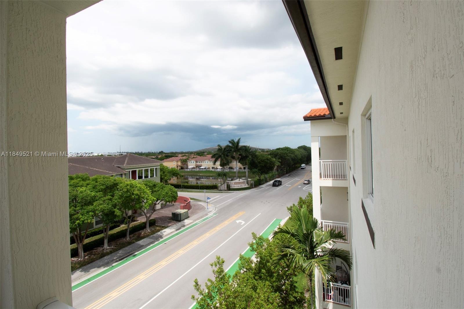 An elevated view shows a street intersection, palm trees, and residential buildings under a cloudy sky — 10950 NW 82nd St # 405, Doral FL 33178, DORAL, FL