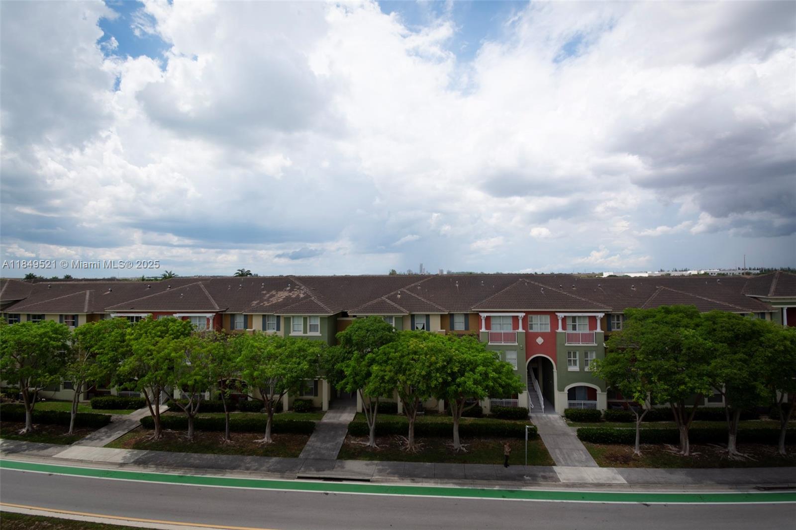 An exterior view of a multi-story apartment complex with green and red accents — 10950 NW 82nd St # 405, Doral FL 33178, DORAL, FL