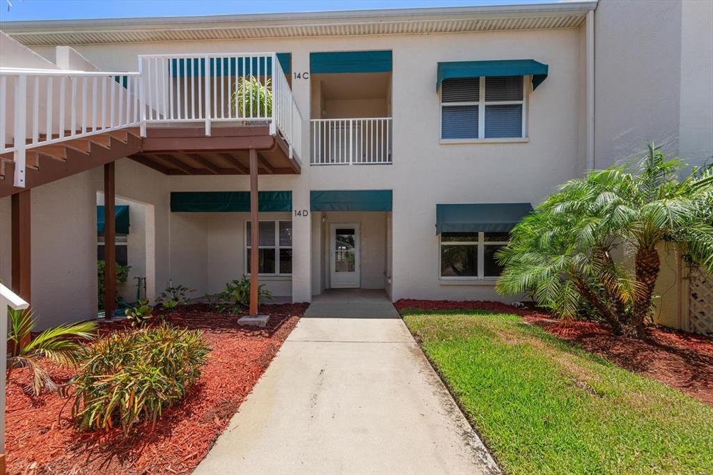 A two-story apartment building exterior features a concrete walkway leading to a ground-floor entrance — 6330 99TH WAY N UNIT 14D, SEMINOLE, FL