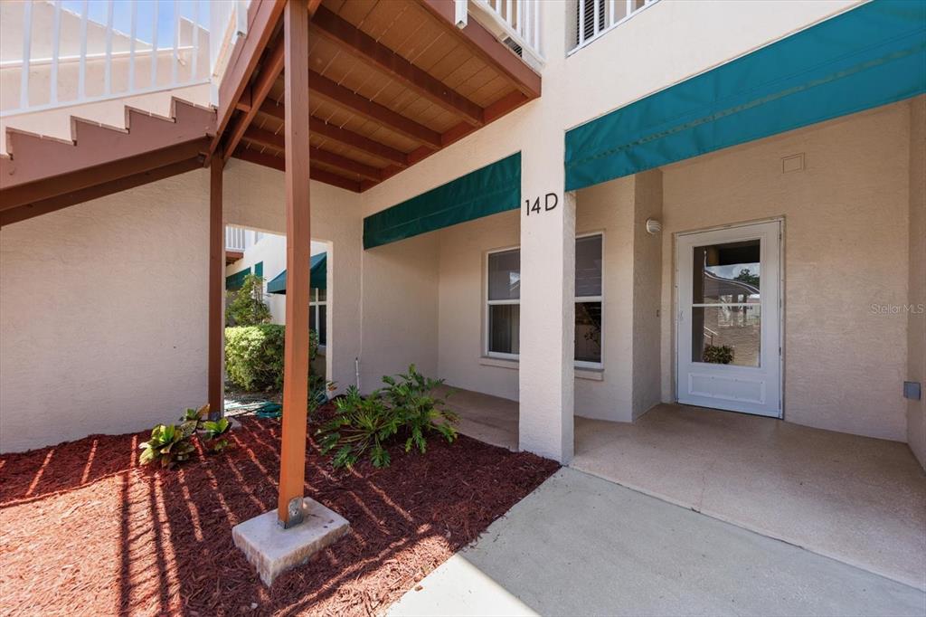 The exterior view shows a ground-level apartment entrance with a covered porch and stairs — 6330 99TH WAY N UNIT 14D, SEMINOLE, FL