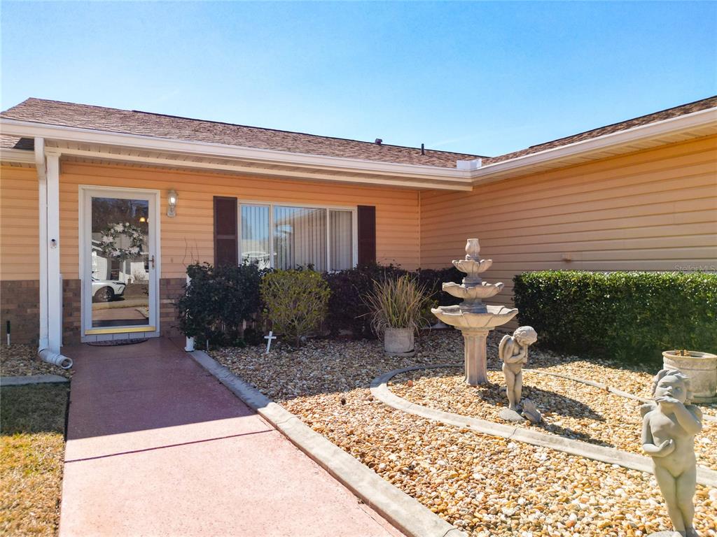 The exterior of a house features a walkway, a tiered fountain, and two cherub statues — 9826 SE 178TH LANE, SUMMERFIELD, FL