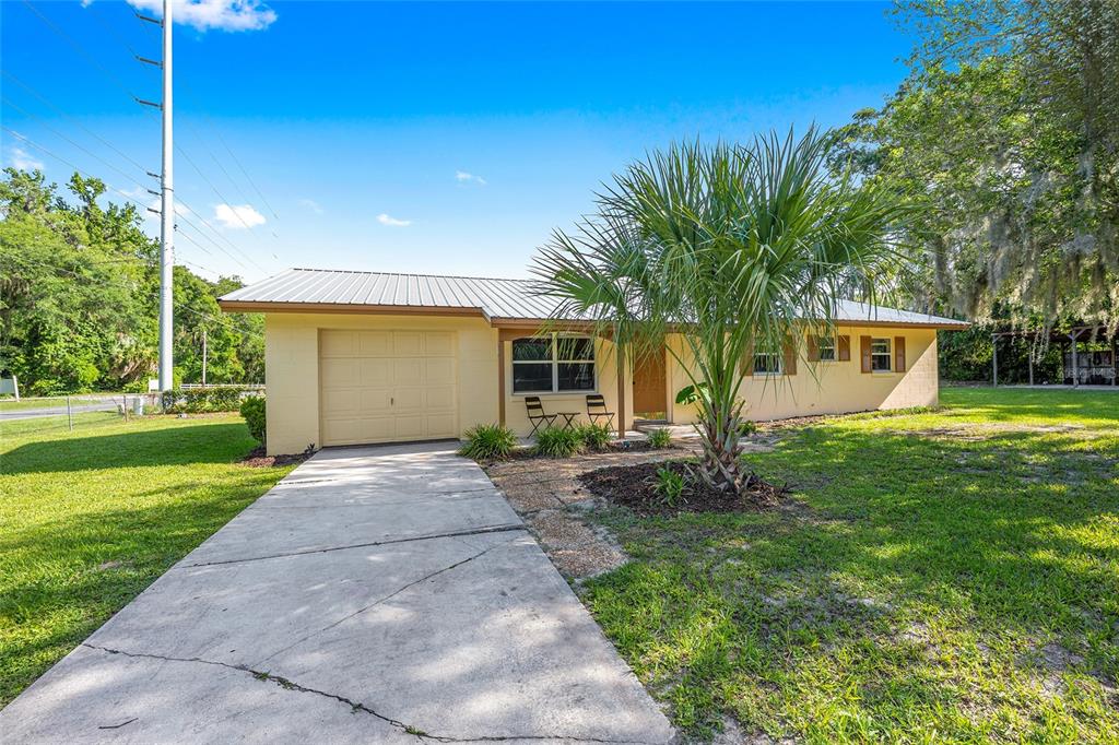 A single-story yellow house with a metal roof, a one-car garage, and a palm tree — 2420 NE 38TH STREET, OCALA, FL