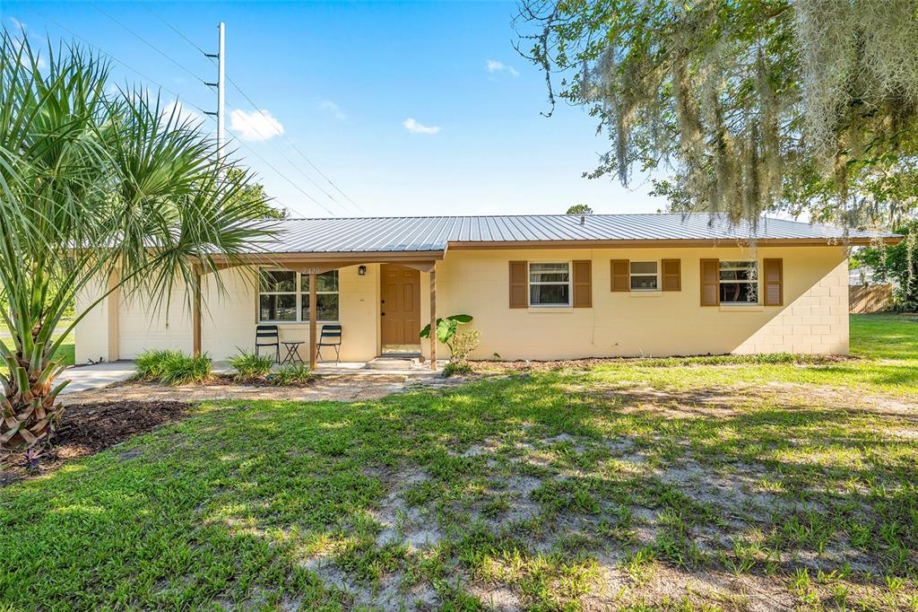 A single-story house with a metal roof, yellow exterior, and a front porch — 2420 NE 38TH STREET, OCALA, FL
