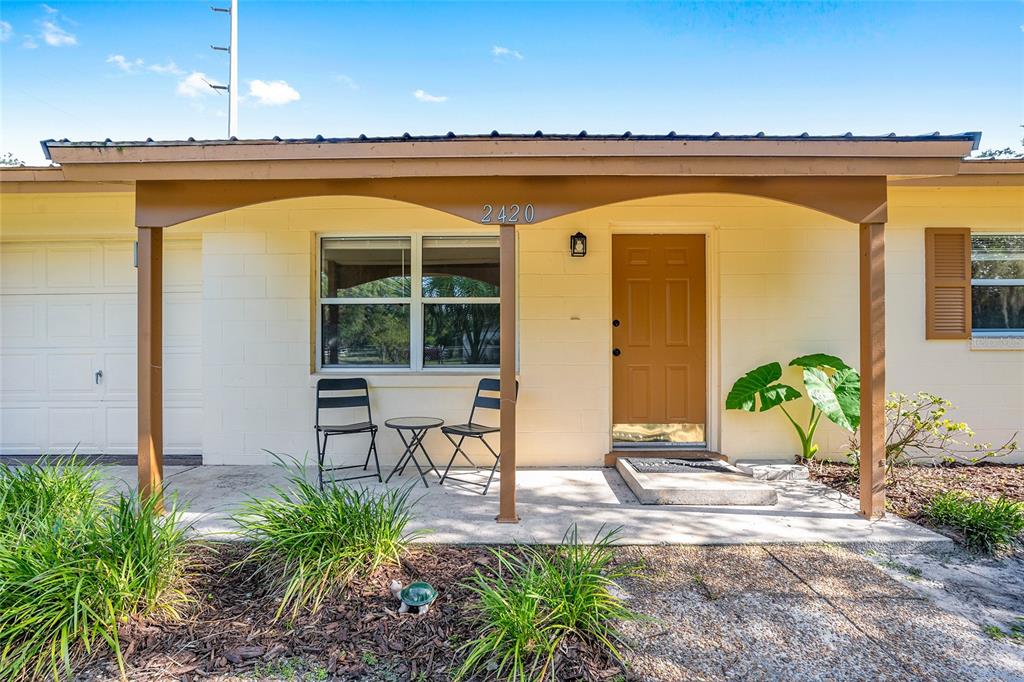 A single-story house exterior features a covered front porch, a brown door, and two chairs — 2420 NE 38TH STREET, OCALA, FL