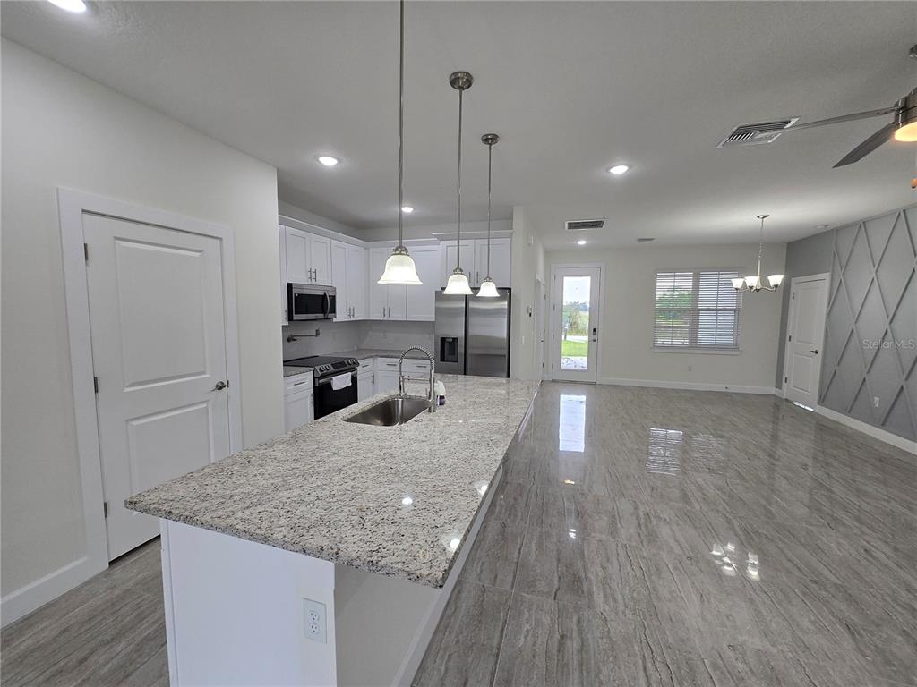 A kitchen with a granite island, white cabinets, and gray tile flooring — 890 E 19TH STREET, ST CLOUD, FL