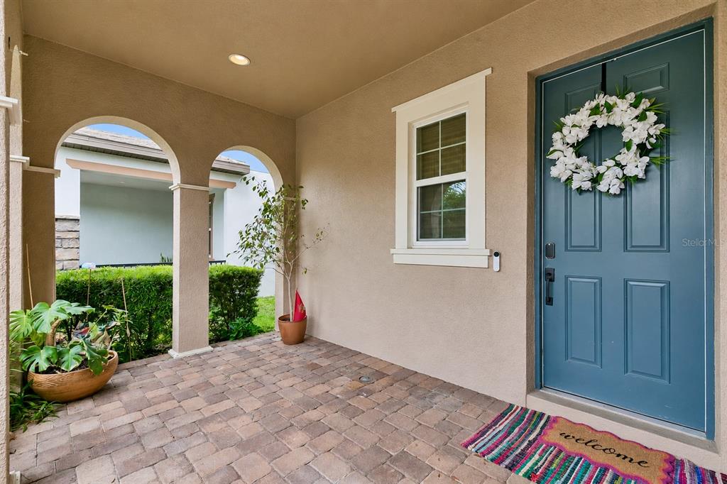 A covered entryway features a blue front door, a brick floor, and arched openings — 17059 HARBOR OAK PARKWAY, WINTER GARDEN, FL