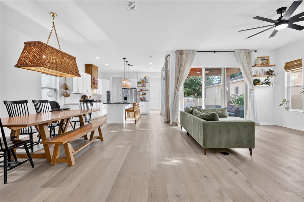An open-concept living and dining area features light wood floors, a kitchen island, and furniture — 17059 HARBOR OAK PARKWAY, WINTER GARDEN, FL