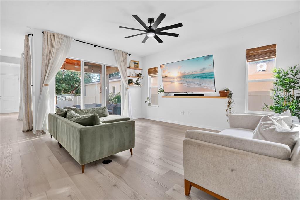 A living room features light wood flooring, a green sofa, a television, and a ceiling fan — 17059 HARBOR OAK PARKWAY, WINTER GARDEN, FL