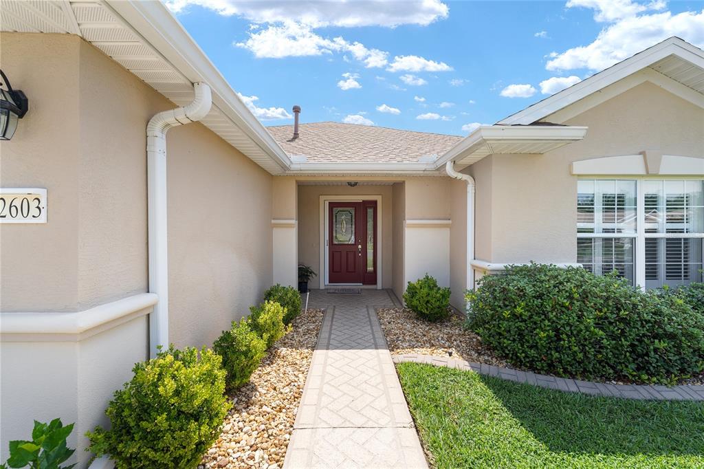 The exterior view shows a tan house with a red front door and walkway — 12603 SE 90TH TERRACE, SUMMERFIELD, FL