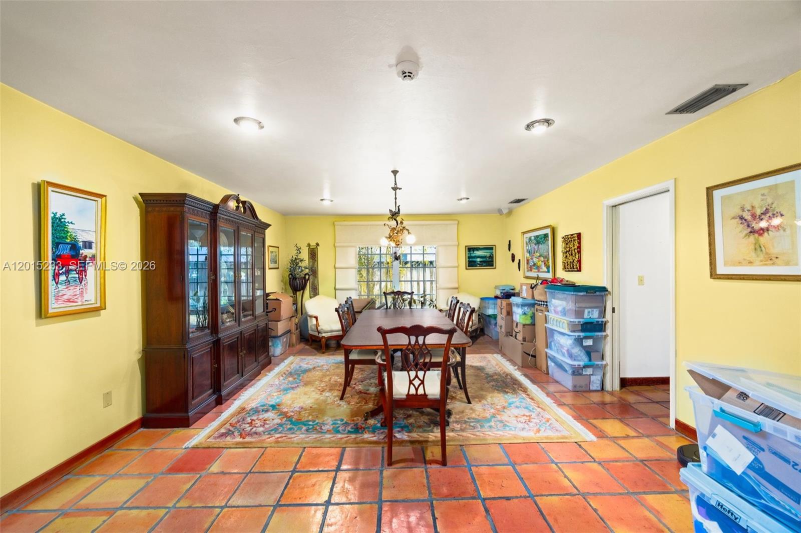 A dining room with yellow walls, tile floors, a wooden table, and a china cabinet — 21141 NE 21st Ct, Miami FL 33179, MIAMI, FL