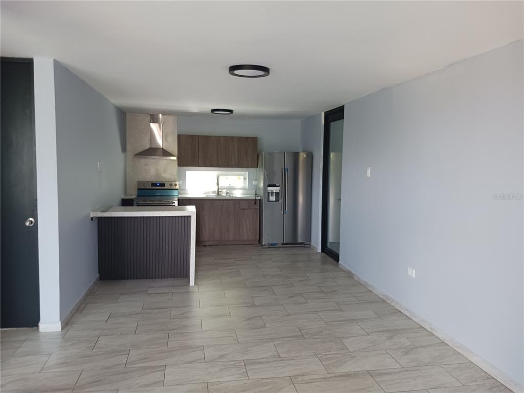 A kitchen with wood cabinets, stainless steel appliances, and a peninsula island on tiled floors — KM. 11.7 RD. 174 INT, BAYAMON, PR