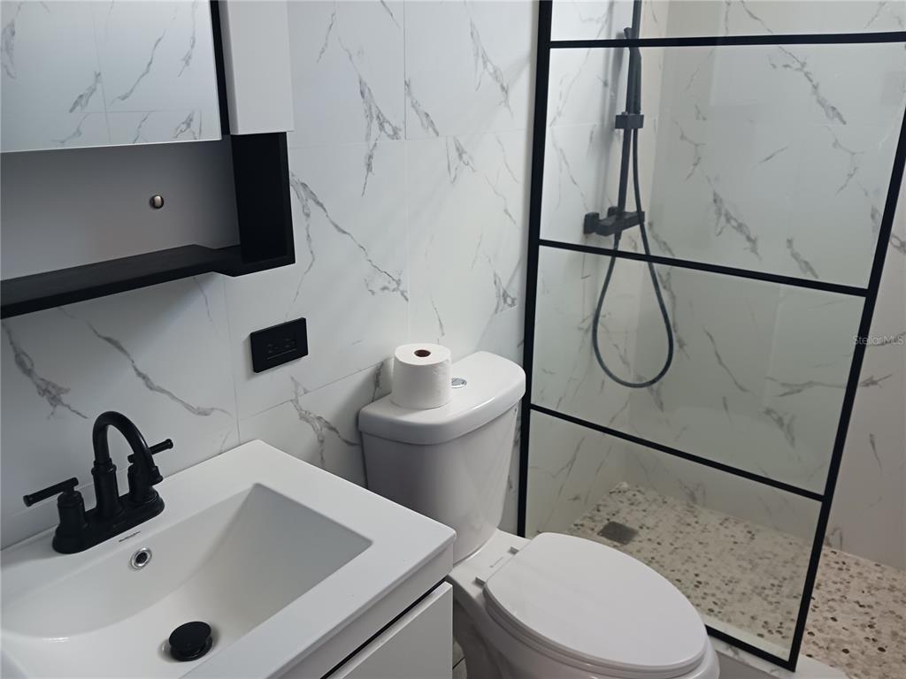 A modern bathroom features white marble-patterned tiles, a black faucet, and a glass-enclosed shower — KM. 11.7 RD. 174 INT, BAYAMON, PR