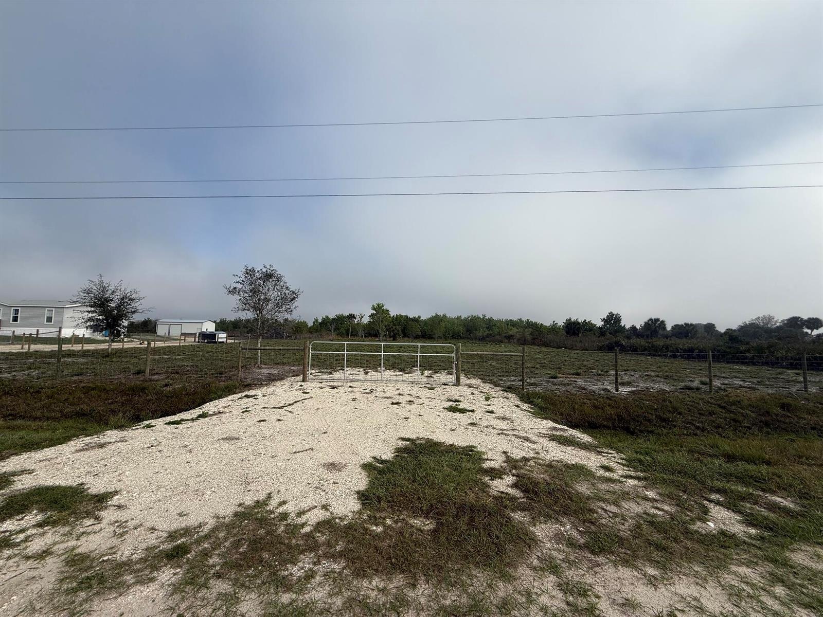 A gravel driveway leads to a metal gate in a fenced, grassy field — 18935 NW 268th Street, Okeechobee FL 34972, OKEECHOBEE, FL