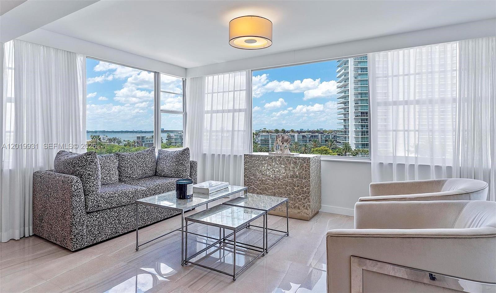 A living room features a patterned sofa, glass coffee tables, and floor-to-ceiling windows with views — 16 Island Ave # 7C, Miami Beach FL 33139, MIAMI BEACH, FL
