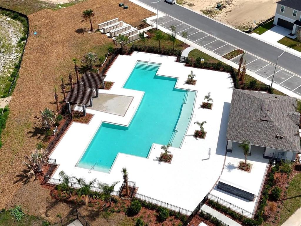 An aerial view shows a community swimming pool with a pergola and adjacent clubhouse — 3676 ROLLING RIDGE BEND, DAVENPORT, FL