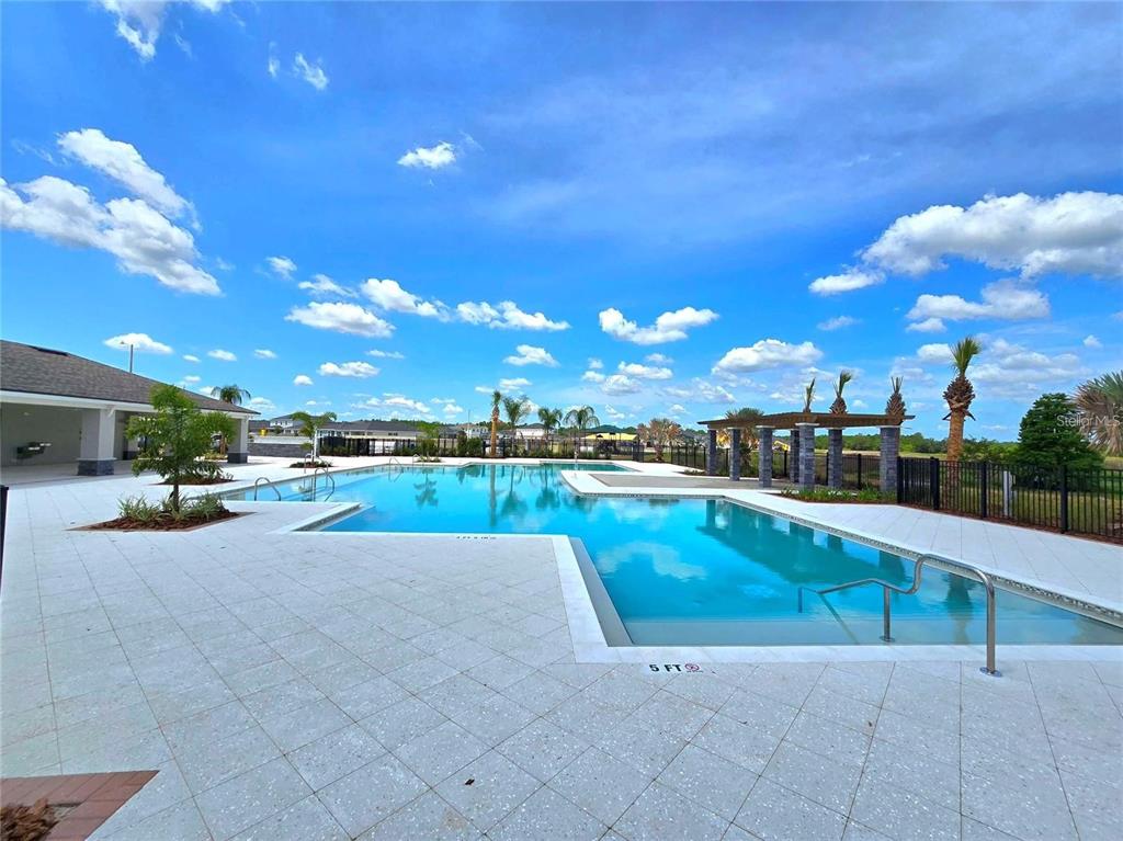 A swimming pool with a surrounding patio and a pergola under a blue sky — 3676 ROLLING RIDGE BEND, DAVENPORT, FL