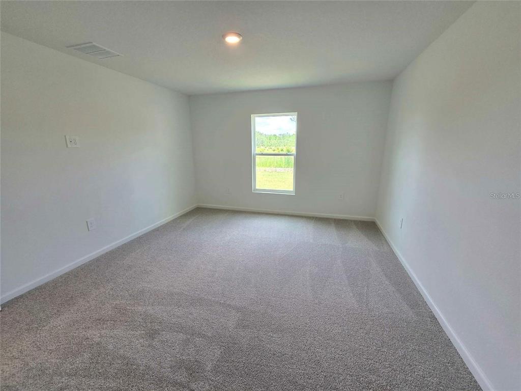 An empty bedroom features white walls, gray carpet, and a single window — 3676 ROLLING RIDGE BEND, DAVENPORT, FL