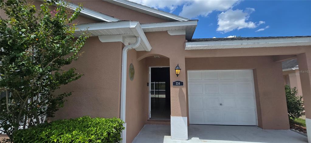 The exterior of a tan house features a white garage door and a front entrance — 334 RESERVE DRIVE, DAVENPORT, FL