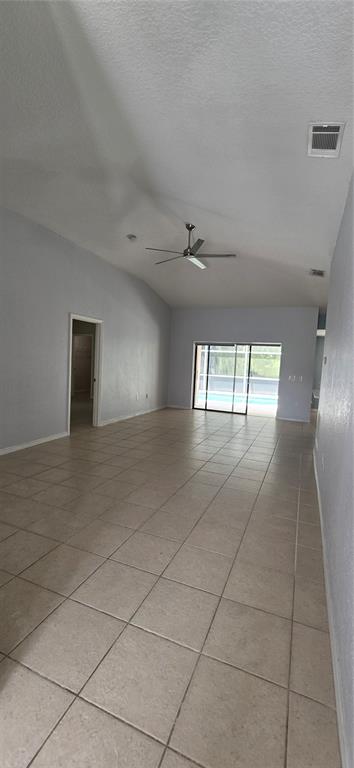 An open-concept living area features light-colored tile flooring, vaulted ceilings, a ceiling fan, and sliding doors — 334 RESERVE DRIVE, DAVENPORT, FL