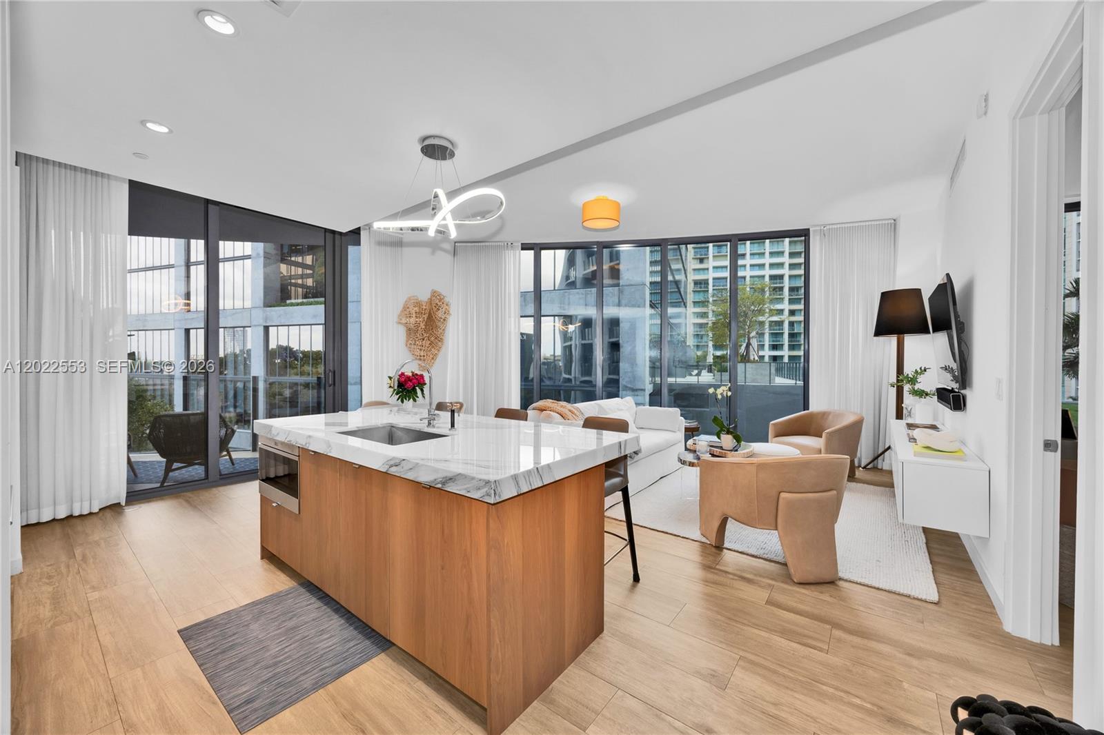 A modern kitchen island with a marble countertop sits in an open-concept living area — 2831 S Bayshore Dr # 705, Miami FL 33133, MIAMI, FL