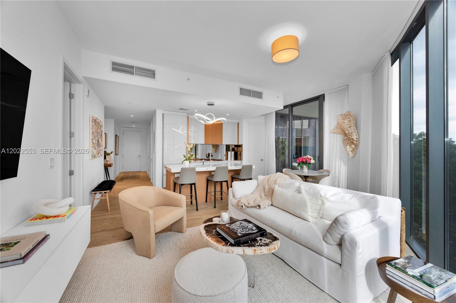 A modern open-concept living room features a white sofa, beige armchair, and kitchen island — 2831 S Bayshore Dr # 705, Miami FL 33133, MIAMI, FL