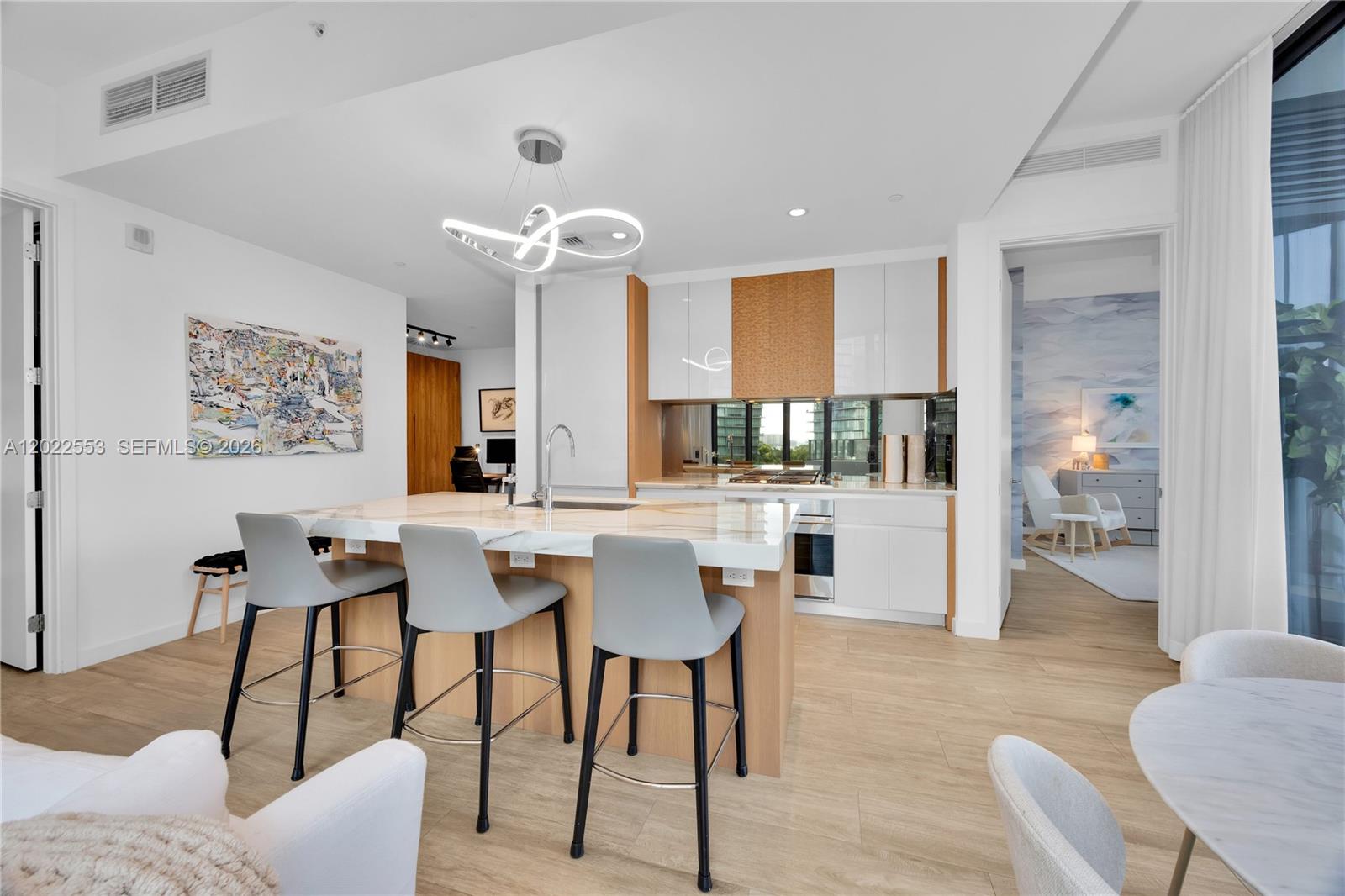 A modern kitchen features a marble-topped island with three gray stools and white cabinetry — 2831 S Bayshore Dr # 705, Miami FL 33133, MIAMI, FL