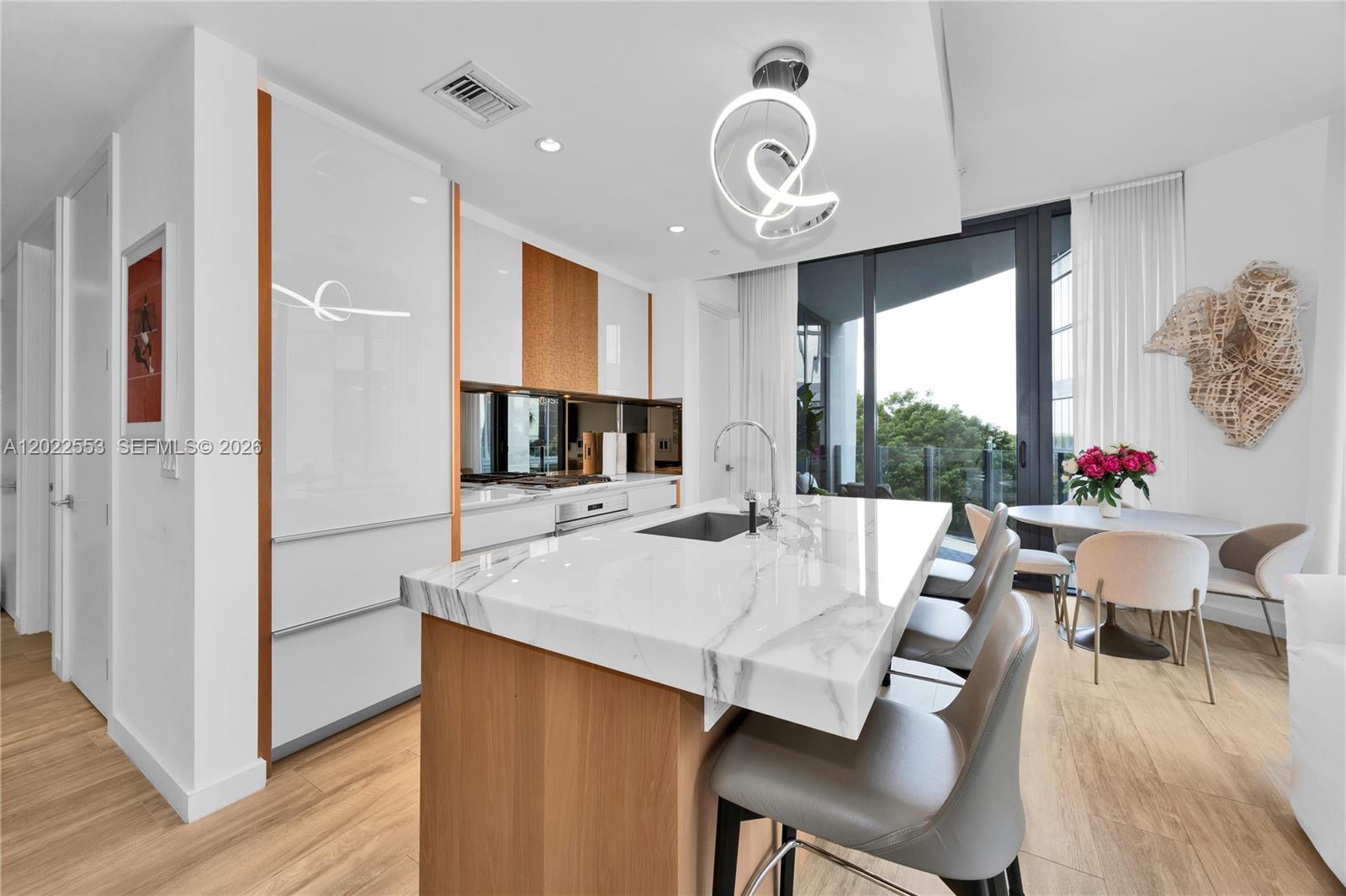 A modern kitchen features a marble-topped island, light wood cabinetry, and floor-to-ceiling windows — 2831 S Bayshore Dr # 705, Miami FL 33133, MIAMI, FL