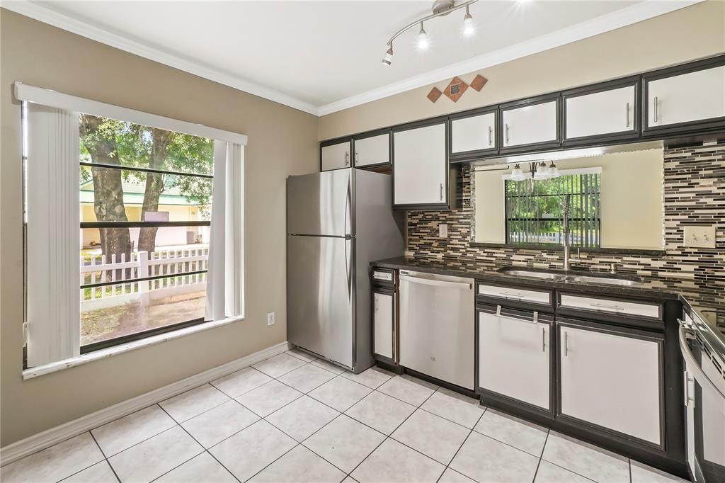 A kitchen with white cabinets, dark trim, stainless steel appliances, and a tiled floor — 5002 CORVETTE DRIVE, TAMPA, FL
