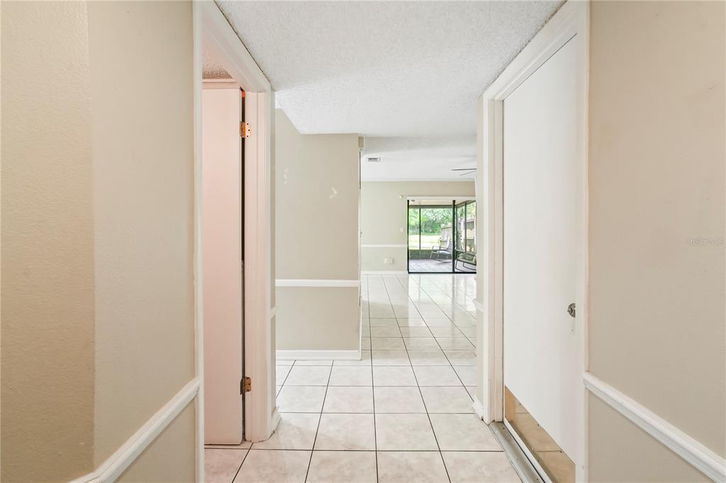A tiled hallway leads to a living area with a sliding glass door to a patio — 5002 CORVETTE DRIVE, TAMPA, FL