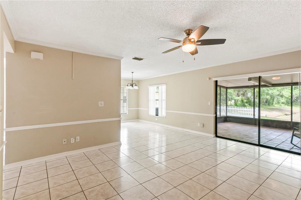 A bright living area features beige walls, white tile flooring, a ceiling fan, and sliding doors — 5002 CORVETTE DRIVE, TAMPA, FL