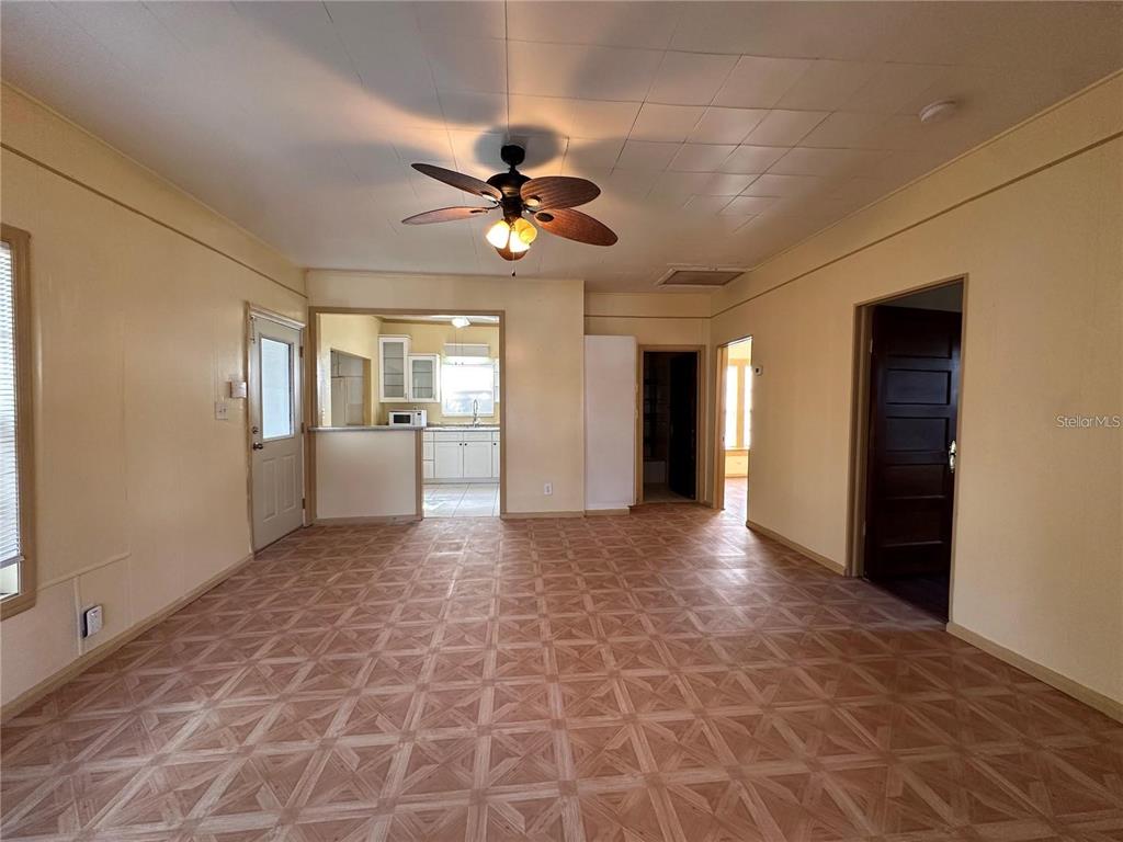 A living room with patterned tile flooring, a ceiling fan, and an adjacent kitchen — 1025 E MAIN STREET, BARTOW, FL