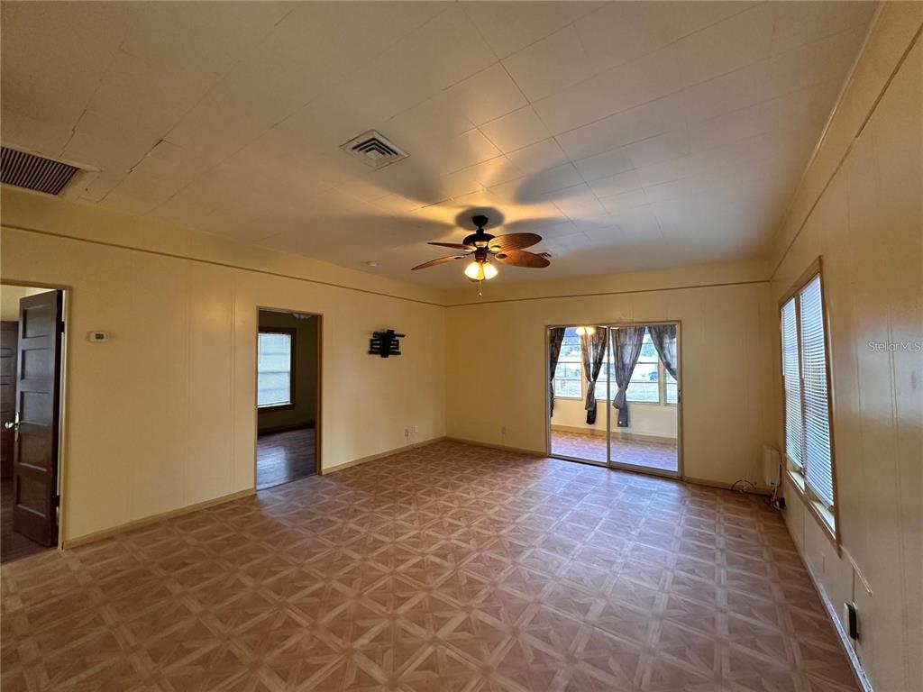 A living room features light yellow walls, patterned vinyl flooring, and a ceiling fan — 1025 E MAIN STREET, BARTOW, FL