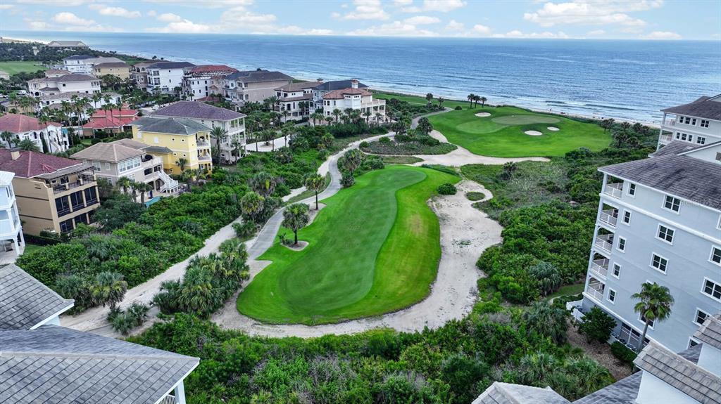 An aerial view shows a golf course fairway nestled between residential buildings and the ocean — 300 CINNAMON BEACH WAY UNIT 221, PALM COAST, FL