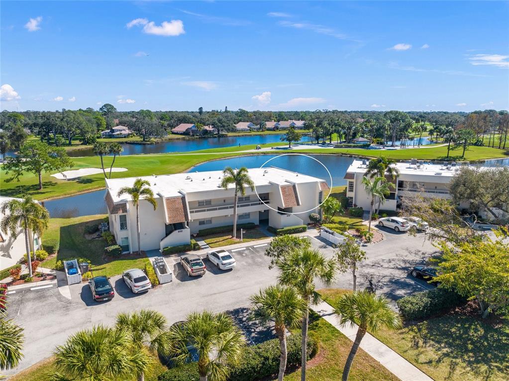 An aerial view shows a multi-story apartment building with a white roof near a lake — 7193 W COUNTRY CLUB DRIVE N UNIT 237, SARASOTA, FL