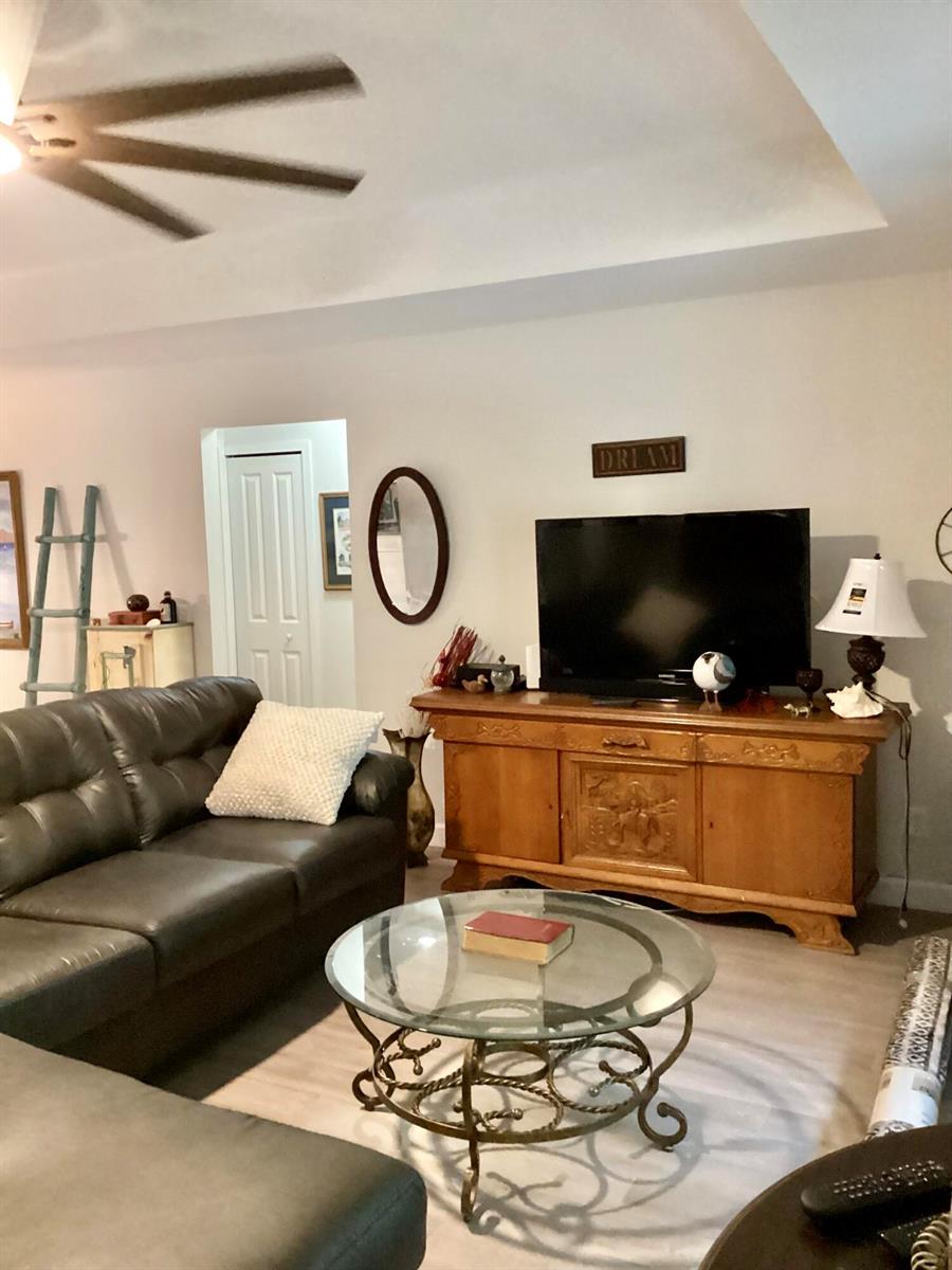 A living room features a dark leather sofa, a glass coffee table, and a wooden media console — 23 Highlands Drive SW, Vero Beach FL 32962, VERO BEACH, FL