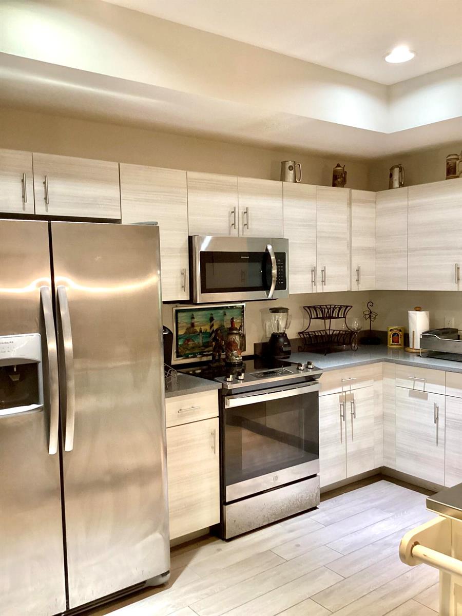 A kitchen features light wood-grain cabinets, stainless steel appliances, and gray countertops — 23 Highlands Drive SW, Vero Beach FL 32962, VERO BEACH, FL