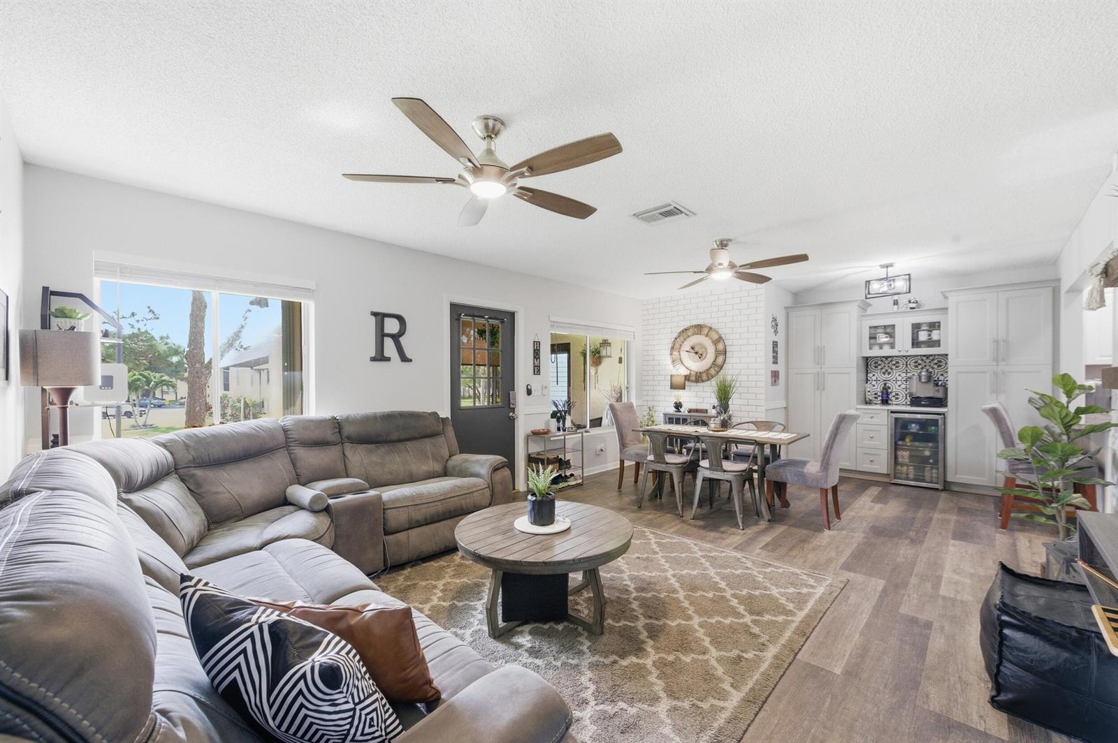 A living room with a sectional sofa, dining area, and kitchen with white cabinetry — 5883 La Paseos Drive # 2, FL 33463, FL