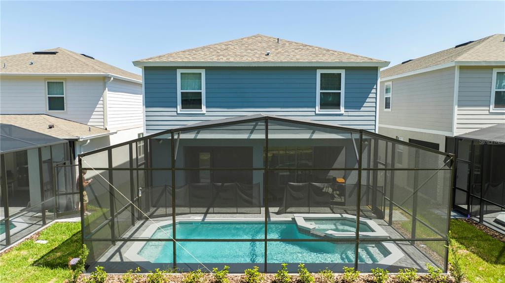 The exterior of a two-story blue house features a screened-in pool and spa — 4458 KAIPO ROAD, DAVENPORT, FL