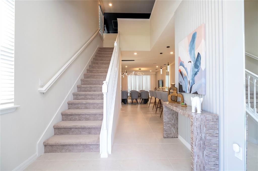 A carpeted staircase leads to an upper level beside a hallway with a console table — 4458 KAIPO ROAD, DAVENPORT, FL