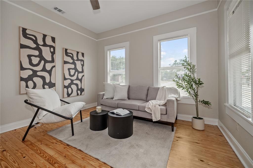 A living room features a grey sofa, an accent chair, two round tables, and artwork — 2506 1/2 E COLUMBUS DRIVE, TAMPA, FL