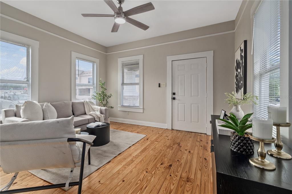 A living room features light-colored walls, wood flooring, a ceiling fan, and a white door — 2506 1/2 E COLUMBUS DRIVE, TAMPA, FL